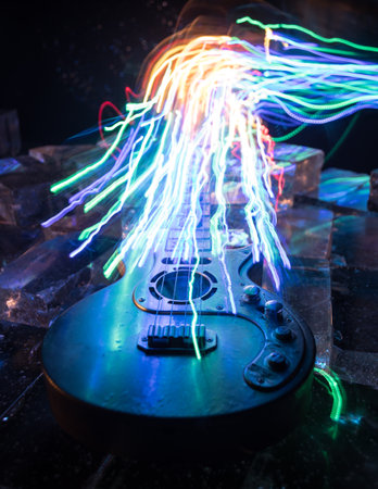 Music Concept: Guitar Miniature on a Dark Background with Vivid Light, Smoke, and Fire Effects. Golden electro guitar under a Dramatic Spotlight. Ice Glass blocks decorの写真素材