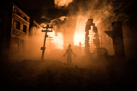 Artwork decoration. A man standing on a road of burnt up city. Apocalyptic view of city downtown as disaster film poster concept. Night scene. City destroyed by war. Selective focusの写真素材