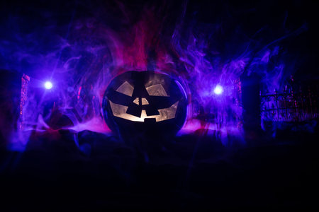 Halloween concept. Cemetery with pumpkin head. Toned light with fog on background. Selective focus. Long shutter shotの写真素材
