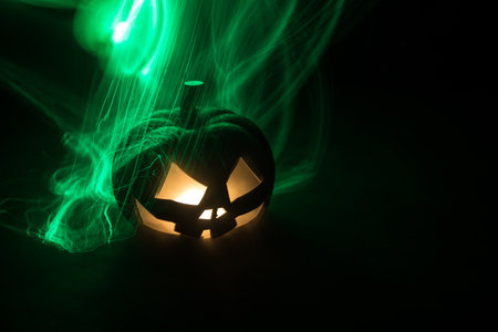 Halloween concept. Halloween pumpkin head in dark on table. Toned light with fog on background. Selective focus. Long shutter shotの写真素材