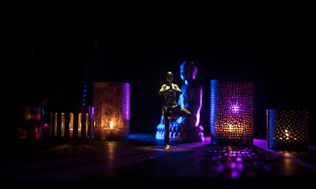 Yoga Concept with Namaste Statue and Oriental-Inspired Miniature on Table. Miniature in selective...