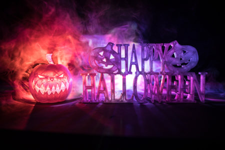 Halloween concept. Halloween pumpkin head in dark on table. Toned light with fog on background. Selective focus. Long shutter shotの写真素材