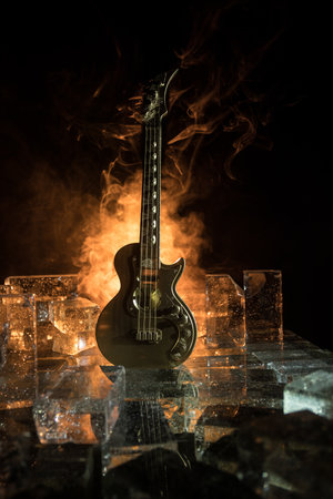 Music Concept: Guitar Miniature on a Dark Background with Vivid Light, Smoke, and Fire Effects. Golden electro guitar under a Dramatic Spotlight. Ice Glass blocks decorの写真素材