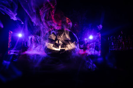 Halloween concept. Cemetery with pumpkin head. Toned light with fog on background. Selective focus. Long shutter shotの写真素材