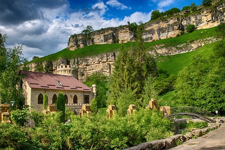 Stone castle with a bridge over a river in the mountains on the background of rocks and woods.