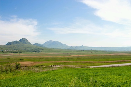 View of the green fields on the background of the blue sky and mountains,  horizon,  landscape. の素材