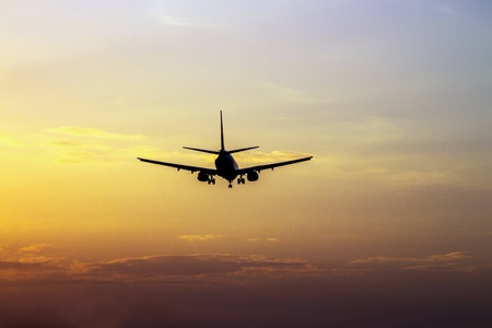 Flying plane in the evening sky at sunset