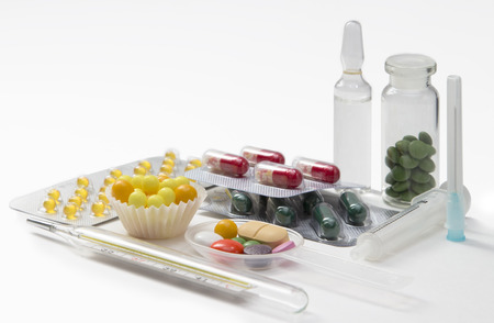 syringe, thermometer, tablets and capsules in blisters on white backgroundの写真素材