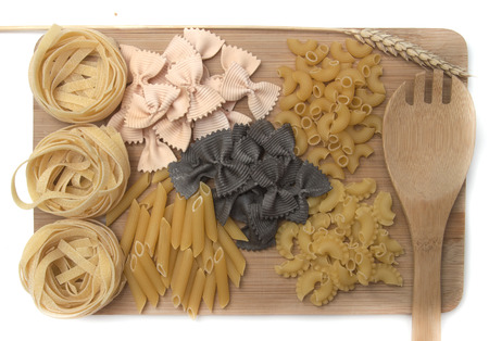 black and golden macaroni, pasta of various kinds, color farfalle with cuttlefish ink and salmon on a wooden board, top viewの写真素材
