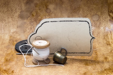 frame label on vintage background old tools for sewing, spool of thread, a thimble and needle, retro styleの写真素材