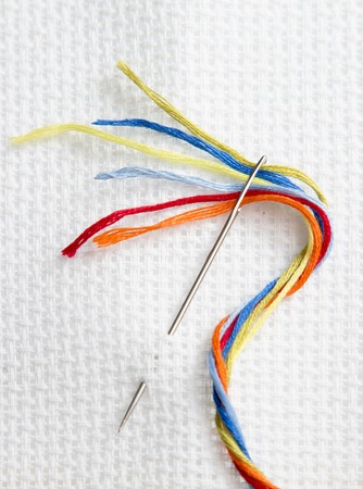white canvas for embroidery and needle with colored thread embroidery floss, passion and work, hand...