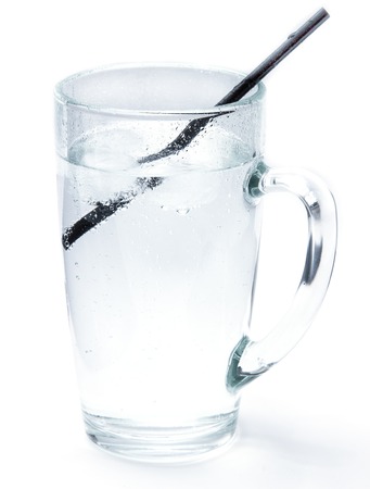 Glass of cold mineral soda water with ice cubes and a cocktail tube isolated on the white background. Mug with crystal clear drinking water, cold and refreshing drink.の写真素材