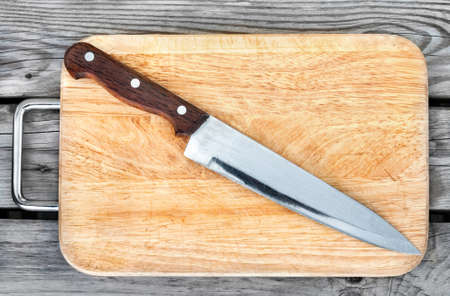 Steel knife and cutting board on a wooden tableの写真素材