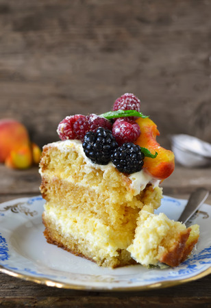 Naked cake with cream, decorated with raspberries, blackberries, peachesの写真素材