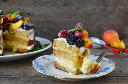 Naked cake with cream, decorated with raspberries, blackberries, peachesの写真素材
