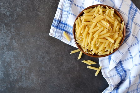 Raw pasta in a bowl on a dark backgroundの写真素材