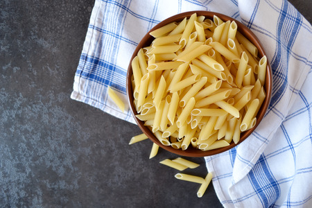Raw pasta in a bowl on a dark backgroundの写真素材