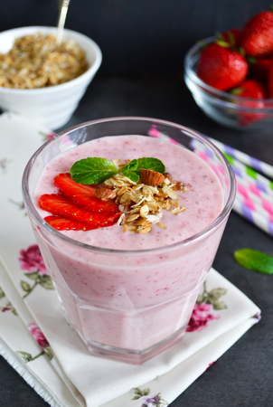 berry smoothies for breakfast with strawberries, oatmeal and almonds in the glass on black backgroundの写真素材
