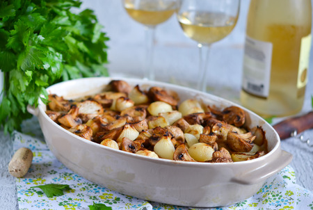 Baked fish with mushrooms, potatoes and onions with a glass of white wine on a concrete backgroundの写真素材