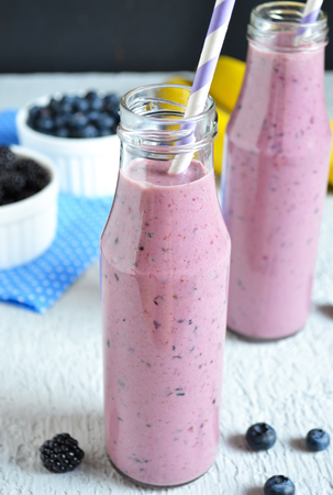 Smoothie with banana, blackberries and blueberries on a black backgroundの写真素材