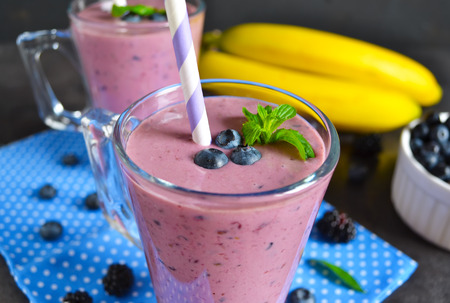 Smoothie with banana, blackberries and blueberries on a black backgroundの写真素材