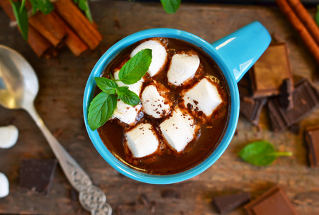 Winter drink - hot chocolate with marshmallows, cinnamon and mint on a wooden background.の写真素材