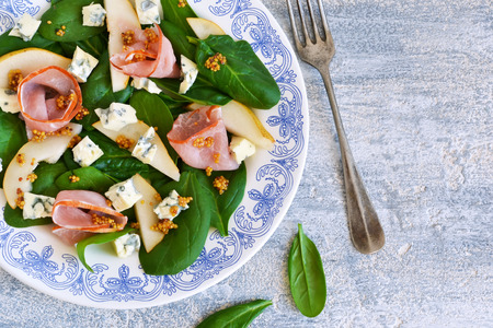 Salad with spinach, blue cheese, ham and pear sauce on a concrete backgroundの写真素材