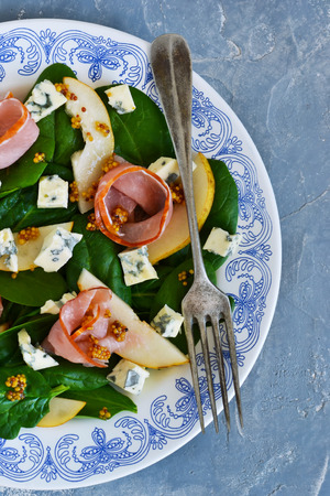 Salad with spinach, blue cheese, ham and pear sauce on a concrete backgroundの写真素材