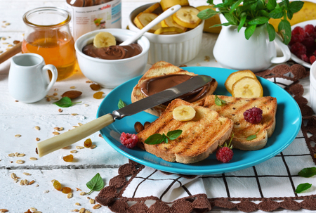 Good morning - toast with walnut, chocolate paste, banana and honey. White food background.の写真素材