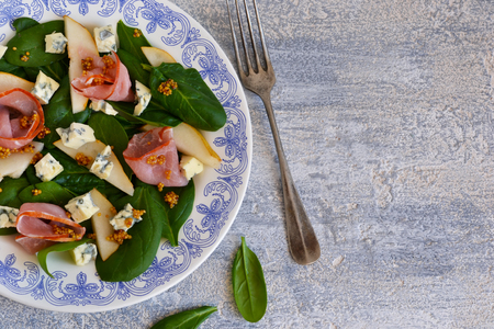 Salad with spinach, blue cheese, ham and pear sauce on a concrete backgroundの写真素材