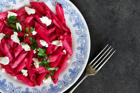 Pasta with beet sauce and feta cheese on a black backgroundの写真素材