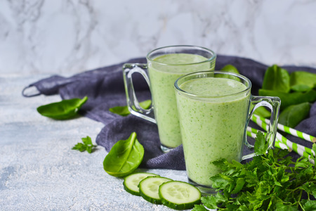 Green vegetable smoothie with avocado, cucumber and spinach on a gray backgroundの写真素材