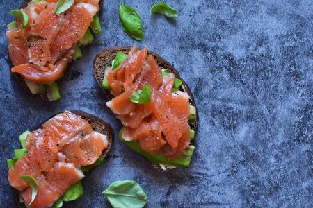 Sandwich with avocado and salmon on a concrete background. View from above.