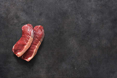 Raw beef steak on a black concrete background. View from above.の写真素材