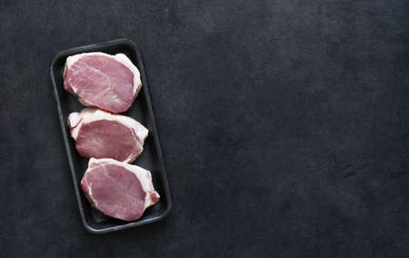 Raw pork steaks in a black tray on a concrete background, top view.の写真素材
