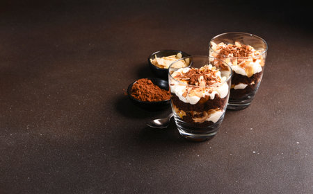 Chocolate cake in a glass with vanilla cream and almonds. A portion of dessert in a glass on a dark background.の写真素材