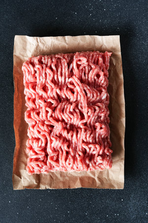 Minced beef on paper on a dark background.