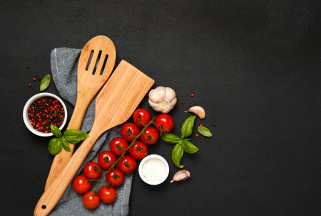 Spatula and kitchen towel and tomatoes on a black background. Food backgroundの写真素材