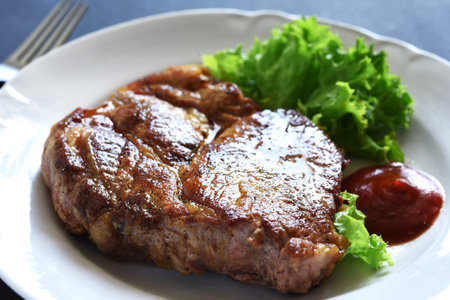 Grilled pork steak with lettuce and sauceの写真素材