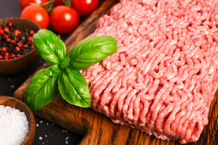 Minced pork and beef on a wooden board. Minced meat with spices on a dark backgroundの写真素材