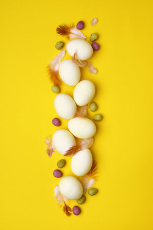 Eggs and feathers on a yellow background. Easter holidayの写真素材