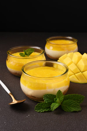Cheesecake with mango in a glass on a brown backgroundの写真素材