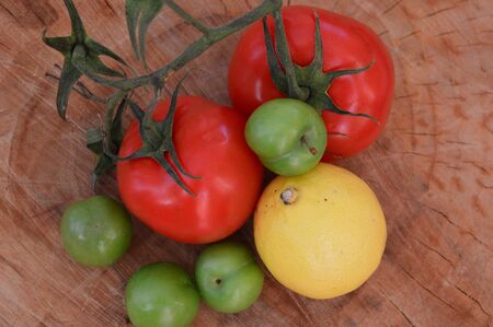 fresh vegetables on a wooden table. Tomato lemon and sour plumの写真素材