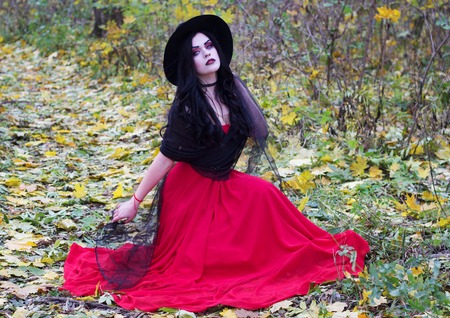 Halloween. The image of a beautiful witch in a red dress.の写真素材