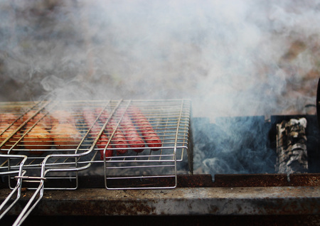Very tasty grilled sausages on a grill in the smoke.