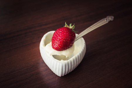 A strawberry with cream on a teaspoon, very tasty food.の写真素材