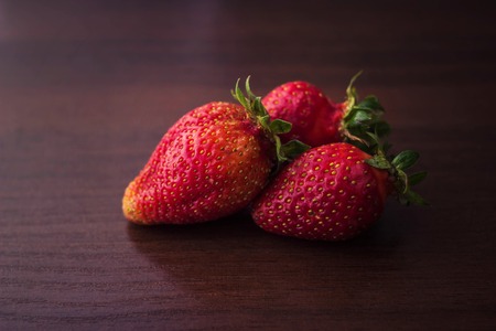 Three berries of strawberries on a tree of chocolate colorの写真素材