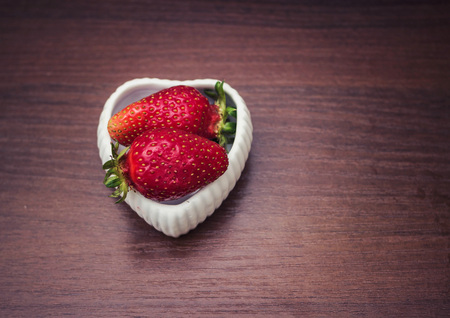 Strawberries in a saucer with a heart shapeの写真素材