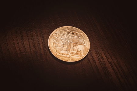Crypto currency in gold. Gold coin bitcoin close-up against a dark wood background.