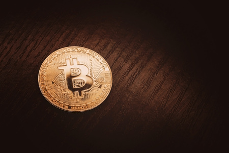 Crypto currency in gold. Gold coin bitcoin close-up against a dark wood background.